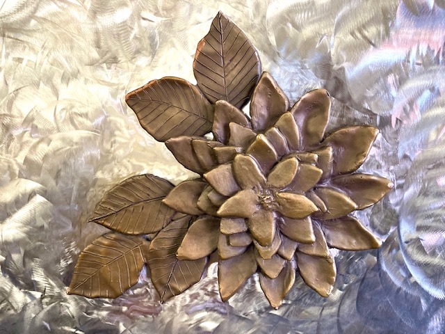Dahlia Flower. A relief sculpture of a Dahlia Flower in Bronze. See this public sculpture at Live Well San Diego in Southeast San Diego, CA